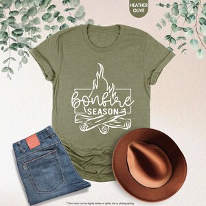 a t - shirt that says bonfire season next to a cowboy hat