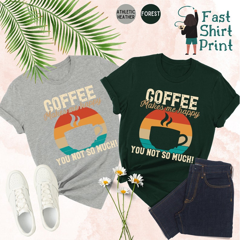 May include: Two t-shirts with a retro sunset design and a coffee cup. The text on the shirts reads "Coffee makes me happy, you not so much!"