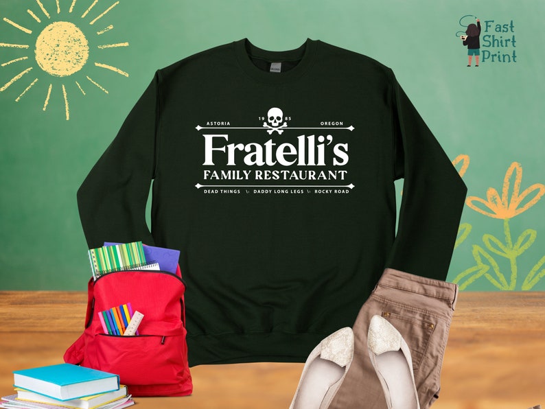 May include: A dark green sweatshirt with a white graphic print of a restaurant logo. The logo says "Fratelli's Family Restaurant" with the words "Astoria" and "Oregon" above and "Dead Things, Daddy Long Legs, Rocky Road" below.