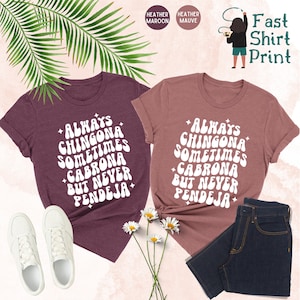 Puede incluir: Dos camisetas con el texto "Always Chingona Sometimes Cabrona But Never Pendeja" en una fuente retro. Las camisetas son de color marr&oacute;n jaspeado y malva jaspeado.