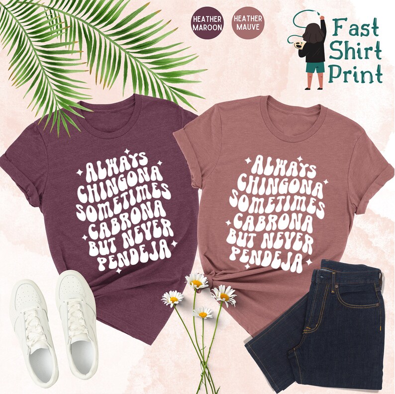 Puede incluir: Dos camisetas con el texto "Always Chingona Sometimes Cabrona But Never Pendeja" en una fuente retro. Las camisetas son de color marr&oacute;n jaspeado y malva jaspeado.