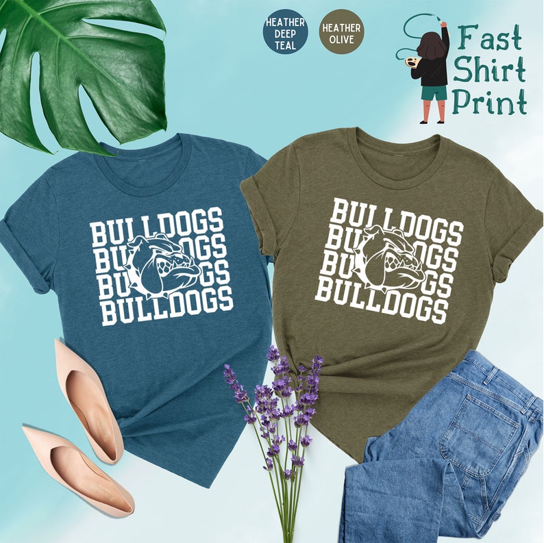 May include: Two t-shirts with the word "Bulldogs" repeated in a stacked pattern. The shirts are in heather deep teal and heather olive colors. The word "Bulldogs" is in white and features a bulldog head graphic.