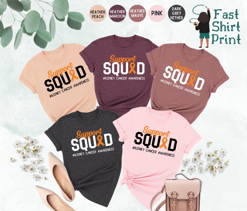 May include: Five t-shirts in different colors with the text "Support Squad" and a ribbon design. The text "#Kidney Cancer Awareness" is below the design. The t-shirts are available in heather peach, heather maroon, heather mauve, pink, and dark grey heather.