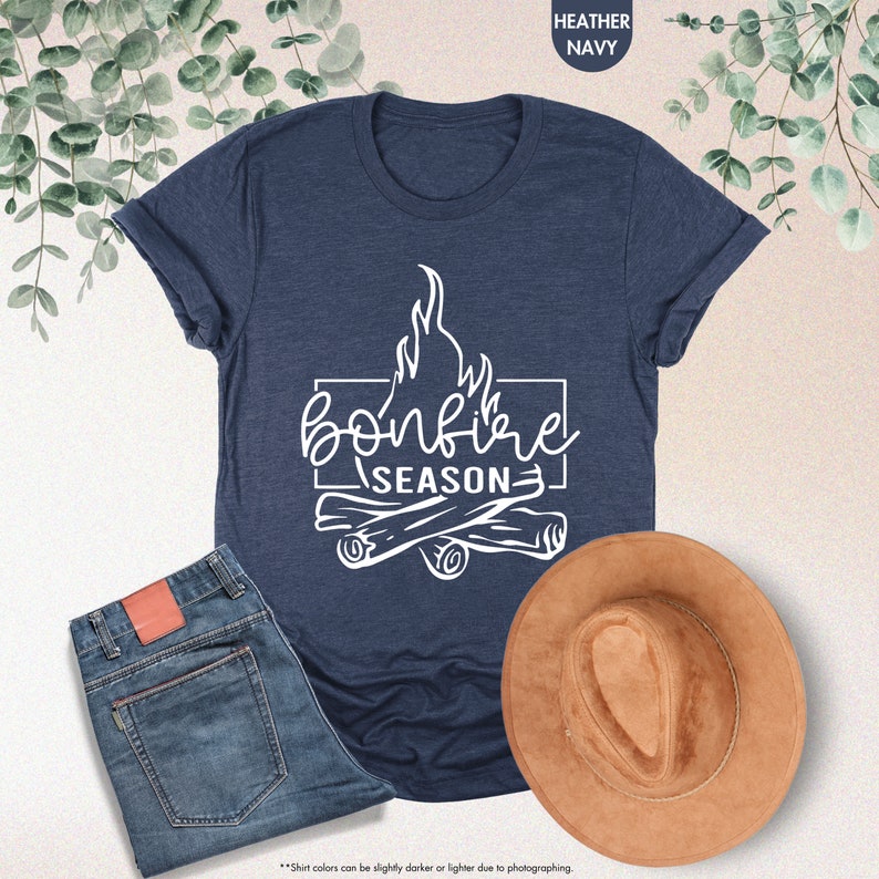 a t - shirt that says bonfire season next to a cowboy hat