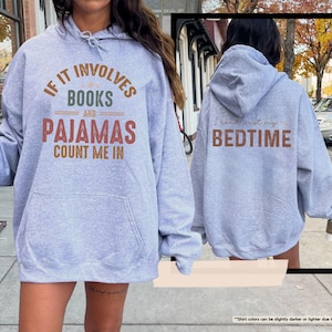 Puede incluir: Una sudadera gris claro con el texto "If it involves books and pajamas count me in" en la parte delantera y "I need more bedtime" en la parte trasera.