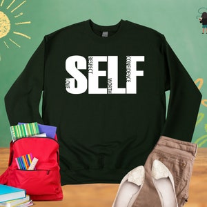 May include: Dark green sweatshirt with white text that reads "SELF" with the words "RESPECT", "LOVE", "WORTH", and "CONFIDENCE" vertically stacked within the letters.