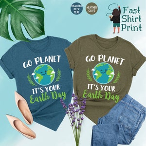 May include: Two t-shirts with a green earth graphic and the text "Go Planet It's Your Earth Day". The shirts are in heather deep teal and heather olive.