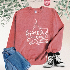 a red sweatshirt that says bonfire season next to a pair of jeans