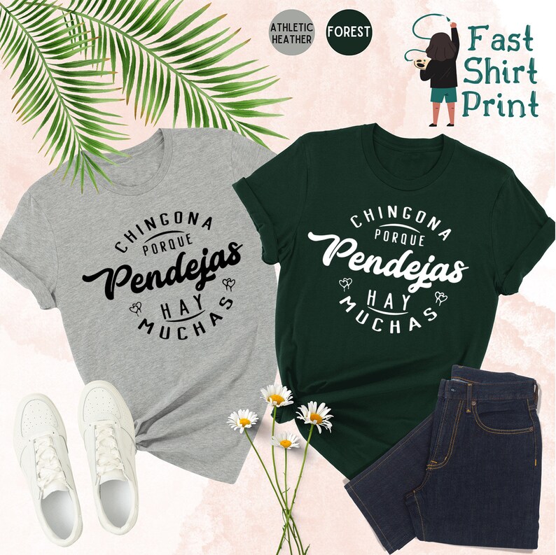 以下が含まれることがあります： 黒と白のテキスト「Chingona Porque Hay Pendejas」が書かれた2枚のTシャツ。左側のTシャツはグレーで、右側のTシャツはグリーンです。