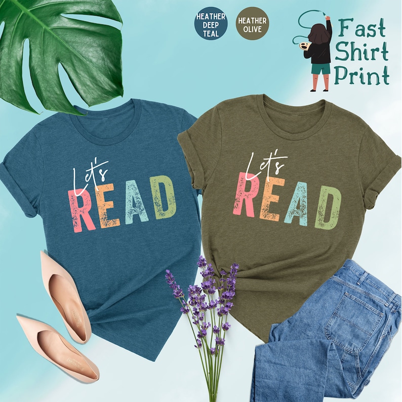 May include: Two t-shirts with the text "Let's Read" in colorful letters. The shirt on the left is teal blue and the shirt on the right is olive green.