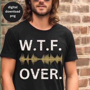 Puede incluir: Camiseta negra con texto blanco que dice "W.T.F. OVER." Un gráfico de onda sonora dorada se encuentra entre las palabras.