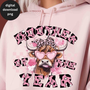 May include: Pink hoodie with a black and pink cow graphic and the text "MOOTHER OF THE YEAR".