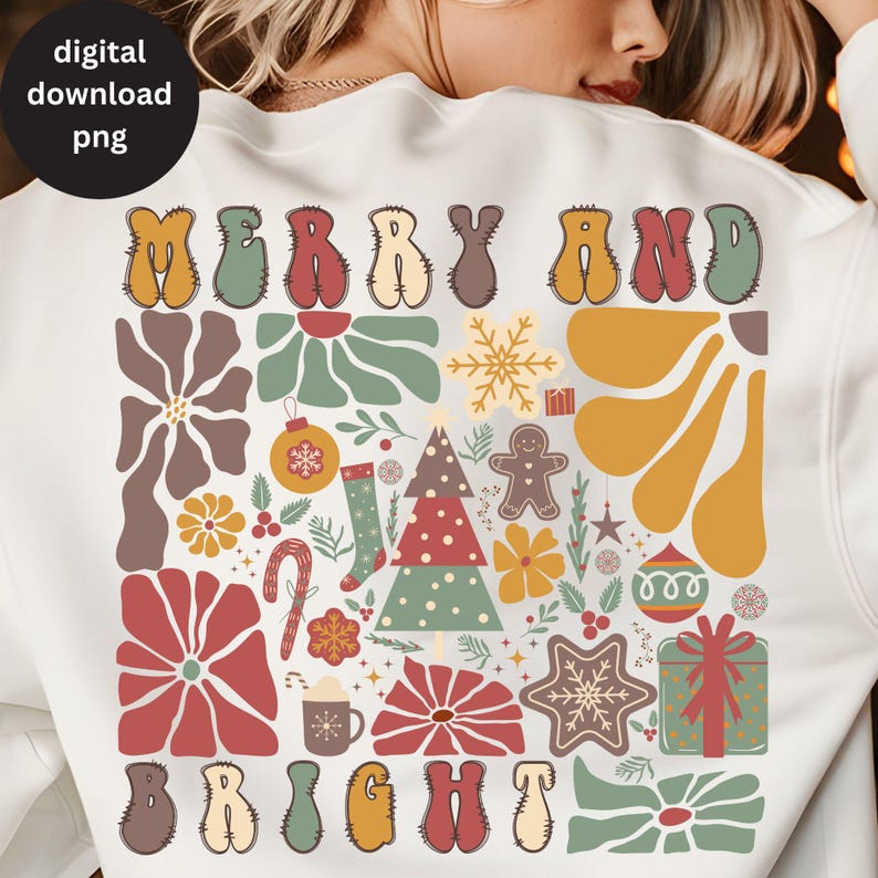 Op de afbeelding: Een wit sweatshirt met een feestelijk ontwerp met de woorden "Merry and Bright" in een retro stijl. Het ontwerp bevat een kerstboom, kerstversiering, sneeuwvlokken en andere feestelijke elementen in rood, groen, geel en bruin.