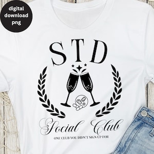 Puede incluir: Camiseta blanca con texto negro que dice "STD Social Club" con un gráfico de dos copas de champán brindando y una corona de hojas. El texto debajo del gráfico dice "Un club al que no te apuntaste."