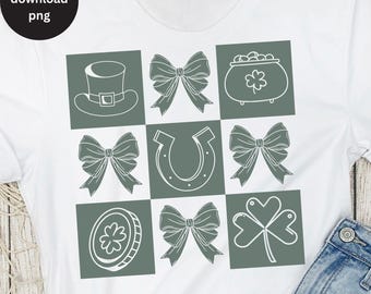 Puede incluir: Una camiseta blanca con un diseño cuadrado verde que presenta varios símbolos irlandeses, incluyendo un trébol, una herradura, una olla de oro, un sombrero de duende y lazos.