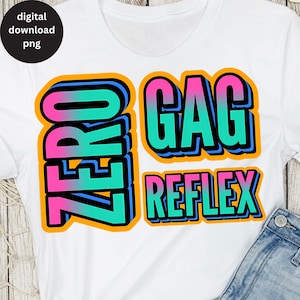 May include: White t-shirt featuring a colourful graphic design that reads "Zero Gag Reflex" in a layered, 3D style. The text is in pink, blue, green, and black with orange outlines.