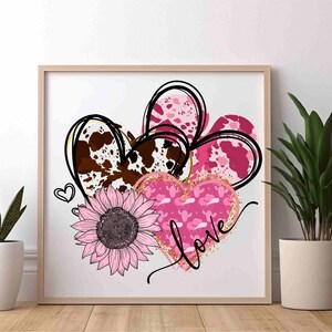Puede incluir: Tres corazones rosas y marrones con un patr&oacute;n de piel de vaca, un coraz&oacute;n rosa con un patr&oacute;n de cactus y sombrero de vaquero, y la palabra "love" en purpurina dorada. Un girasol rosa se encuentra en el centro de los corazones.
