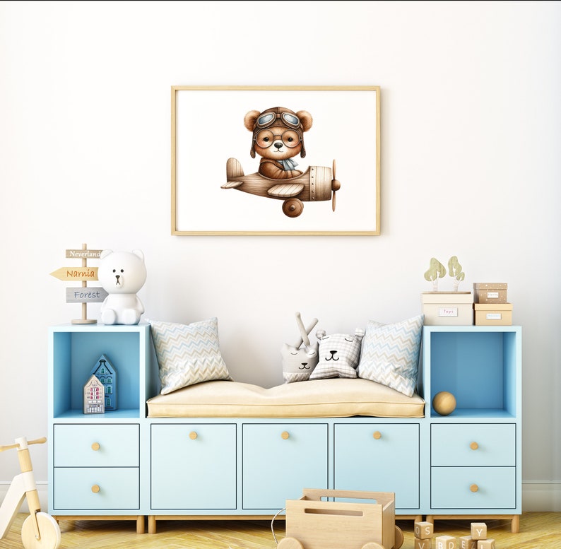 May include: A light blue toy storage bench with a brown cushion and a framed print of a brown bear wearing aviator goggles and flying a brown airplane. The print is on a white background. The bench has four drawers and two open shelves. There are various toys on the shelves, including a white stuffed bear, a wooden toy truck, and a wooden toy airplane.