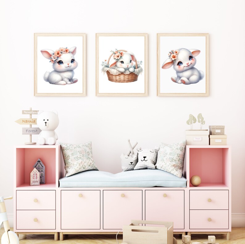 Puede incluir: Tres impresiones enmarcadas de conejos blancos con diademas florales. Los conejos est&aacute;n en diferentes poses, uno est&aacute; sentado, otro est&aacute; en una cesta y el tercero est&aacute; sentado con las patas cruzadas. Las impresiones est&aacute;n en una pared blanca en una guarder&iacute;a.