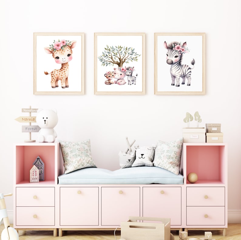 May include: Three framed watercolor illustrations of animals with floral headbands. The first illustration shows a giraffe, the second shows a tiger, a lion, and a zebra, and the third shows a zebra. The illustrations are hung on a white wall above a pink and white storage bench.