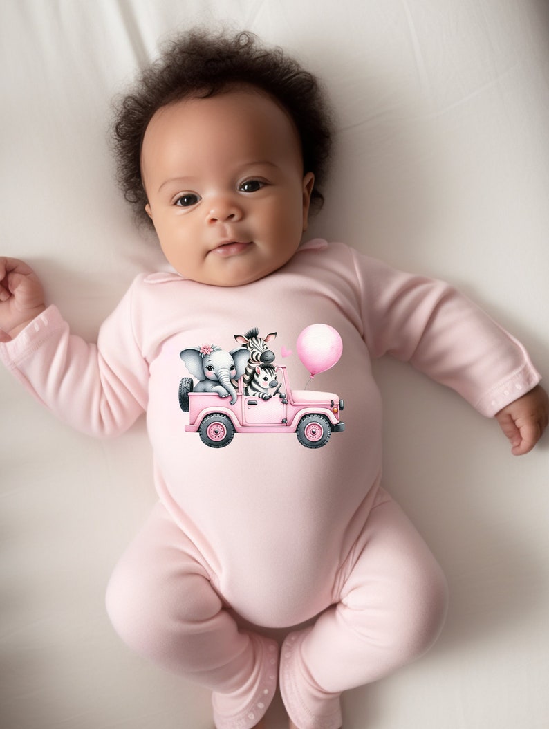 May include: A pink baby onesie with a graphic of a pink jeep with a zebra and elephant riding in it. The jeep has a pink balloon attached to the back.