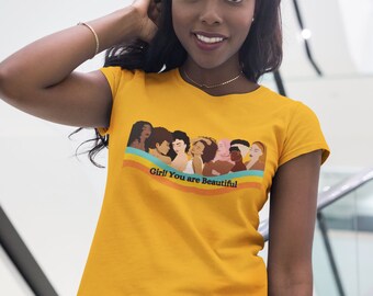 May include: A yellow t-shirt with a graphic of a group of women of different ethnicities and skin tones. The graphic is accompanied by the text "Girl! You are Beautiful".