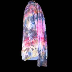 Może przedstawiać: Koszula z długim rękawem zapinana na guziki z żywym wzorem tie-dye w odcieniach r&oacute;żu, fioletu, błękitu i ż&oacute;łci. Koszula posiada klasyczny kołnierzyk, mankiet zapinany na guzik przy rękawie oraz widoczne zapięcie na guzik przy nadgarstku.