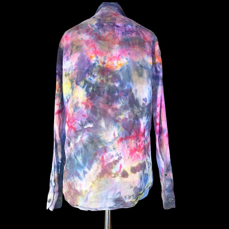 Może przedstawiać: Koszula z długim rękawem zapinana na guziki, ozdobiona żywym wzorem tie-dye z mieszanką odcieni r&oacute;żu, fioletu, błękitu, ż&oacute;łci i czerni. Odzież posiada klasyczny kołnierzyk, pełną listwę guzikową z przodu oraz mankiety zapinane na guziki.