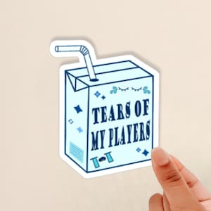 May include: A blue and white cartoon juice box with a straw sticking out of the top. The juice box says "Tears of My Players" with a cartoon eye and a few water drops around it.