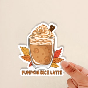 May include: A sticker featuring a pumpkin spice latte with whipped cream and cinnamon sticks. The latte has dice inside, and the text "Pumpkin Dice Latte" is at the bottom.