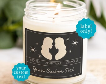 May include: A clear glass candle jar with a black rectangular label featuring two white silhouettes facing each other, star icons, and the text GENTLE ADAPTABLE CURIOUS and Your Custom Text. The candle has a lit wick and white wax inside.