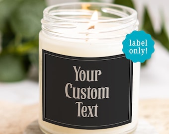 May include: A clear glass candle jar filled with white wax and a lit wick. The jar features a rectangular black label with the text "Your Custom Text" in a serif font. A small turquoise scalloped sticker reads "label only!" in white text.