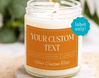 May include: A clear glass candle jar filled with white wax and a lit wick. The jar features an orange rectangular label with the white text YOUR CUSTOM TEXT, CUSTOM TEXT, and Your Custom Text. A blue circular sticker reads label only!