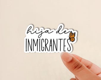 May include: A die-cut sticker featuring the text "hija de INMIGRANTES" in a combination of black cursive and sans-serif fonts. An orange and black monarch butterfly illustration is positioned to the right of the text on a white background.
