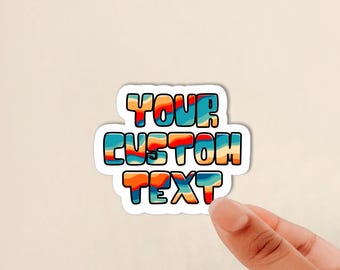 May include: A custom sticker featuring the text YOUR CUSTOM TEXT in a bold, rounded font. The letters display a wavy, multi-colored pattern of orange, red, light blue, and cream stripes, all outlined in a thick black border against a white background.