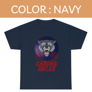 May include: A navy blue t-shirt with a graphic of a snarling wolf's face in a purple circle with red claw marks and the text "CARING RULES" in red.