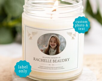 May include: A clear glass jar candle with a white wax fill and a lit wick. The label features an oval photograph of a person, two dove illustrations, and the text: IN LOVING MEMORY OF RACHELLE BEAUDRY, Forever remembered with love gratitude and cherished memories that will remain in our hearts.