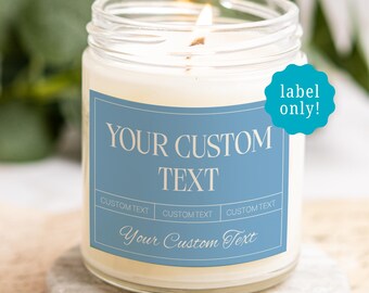 May include: A clear glass jar candle with a lit wick and a blue rectangular label. The label features the text "YOUR CUSTOM TEXT" in large white letters, three smaller "CUSTOM TEXT" boxes, and "Your Custom Text" in script font.