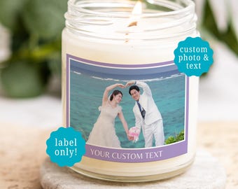 May include: A clear glass jar candle with a white wax fill and a lit wick. The label features a photograph of a couple in wedding attire forming a heart shape with their arms against a blue ocean background, with the text YOUR CUSTOM TEXT.