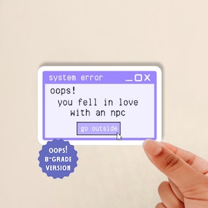 May include: A rectangular sticker featuring a purple computer window graphic with the text system error, oops! you fell in love with an npc, and a button labeled go outside. A separate blue star-shaped sticker reads oops! B-GRADE VERSION.