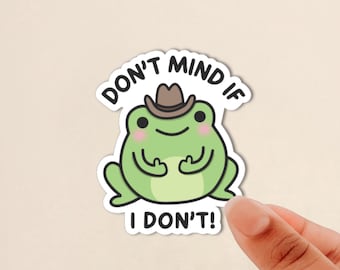 May include: A die-cut sticker featuring a light green cartoon frog wearing a brown cowboy hat. The frog has pink cheeks and is making a hand gesture. The text above and below the frog reads, DON'T MIND IF I DON'T! in bold black letters.