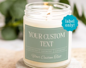 May include: A clear glass candle jar with a lit wick and a sage green rectangular label. The label features the text "YOUR CUSTOM TEXT" in a serif font, three "CUSTOM TEXT" fields, and "Your Custom Text" in script. A blue sticker says "label only!"