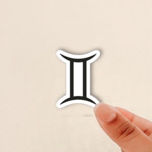 May include: A sticker featuring the Gemini zodiac symbol, which consists of two vertical black lines connected by curved horizontal lines at the top and bottom, set against a white background with a thin white border surrounding the black design.