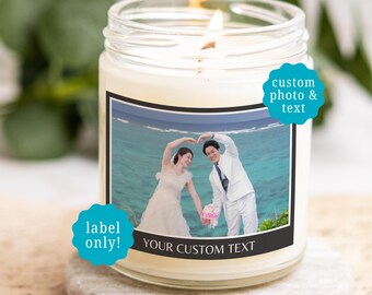 May include: A clear glass candle jar with a white wax fill and a lit wick. The label features a photograph of a couple in wedding attire forming a heart shape with their arms against an ocean backdrop, with the text YOUR CUSTOM TEXT below.