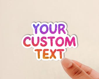 May include: A die-cut sticker featuring the words YOUR CUSTOM TEXT in a bold, sans-serif font. The letters have a vibrant, multi-colored glitter gradient that transitions from purple at the top to pink in the middle and orange at the bottom.