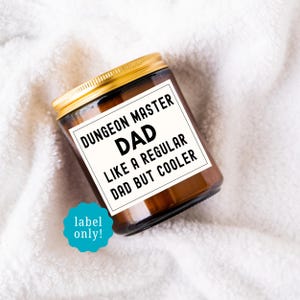 May include: A brown glass jar with a gold lid, featuring a white label with black text that reads "DUNGEON MASTER DAD LIKE A REGULAR DAD BUT COOLER." A teal label that says "label only!" is also visible.