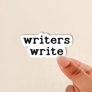 May include: A die-cut sticker featuring the black text "writers write" in a rounded, bold, sans-serif font. The sticker has a white border and is shaped to follow the contour of the two lines of text, creating a clean and legible design.