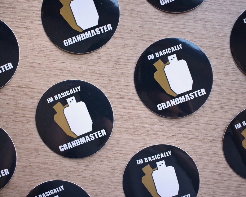 High quality glossy vinyl sticker in a circle shape with a black background. There are 2 shooting targets, one white and one brown with the words Im Basically Grandmaster. A humorous sticker for USPSA competitive shooters.