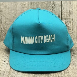 May include: A turquoise blue baseball cap with a white embroidered logo that says "Panama City Beach".