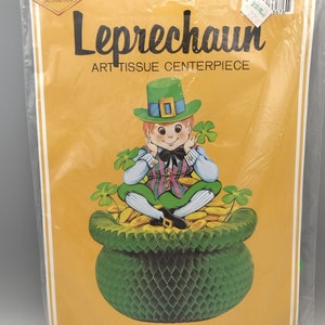 May include: A green leprechaun art tissue centrepiece. The leprechaun is sitting on a pot of gold with a shamrock on top. The pot is 11.5 inches tall or 29.2 cm.